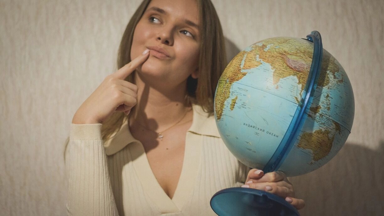 На фото: девушка с глобусом в руках