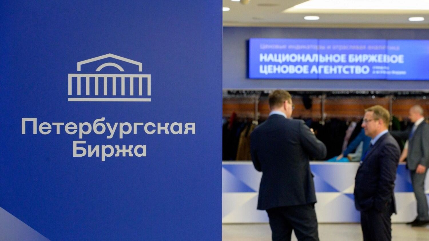 Сотрудники Петербургской биржи на фоне логотипа биржи