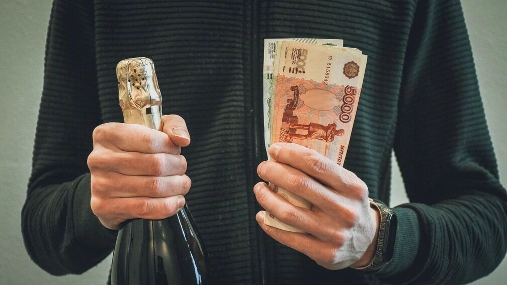 Человек с бутылкой шампанского и купюрами в руках