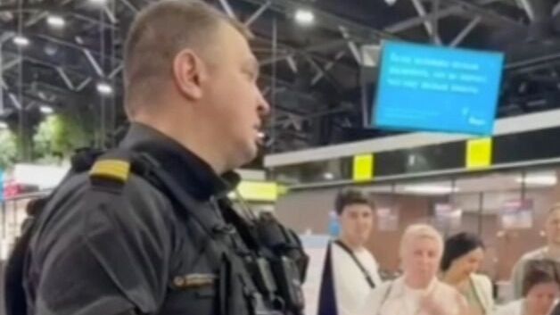 Представитель авиакомпании перед толпой пассажиров отмененных рейсов
