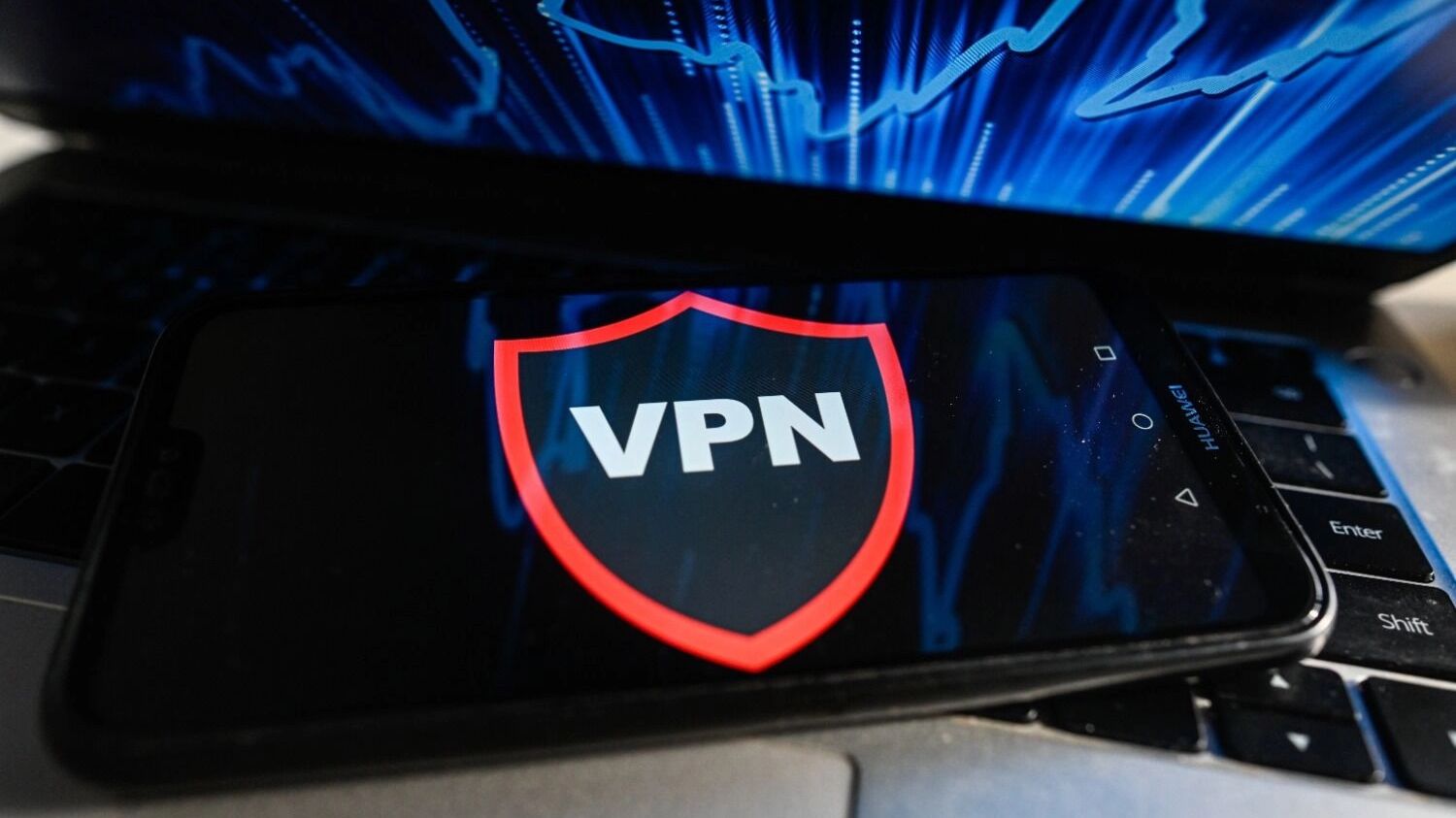 Значек VPN на экране мобильнго телефона на фоне ноутбука