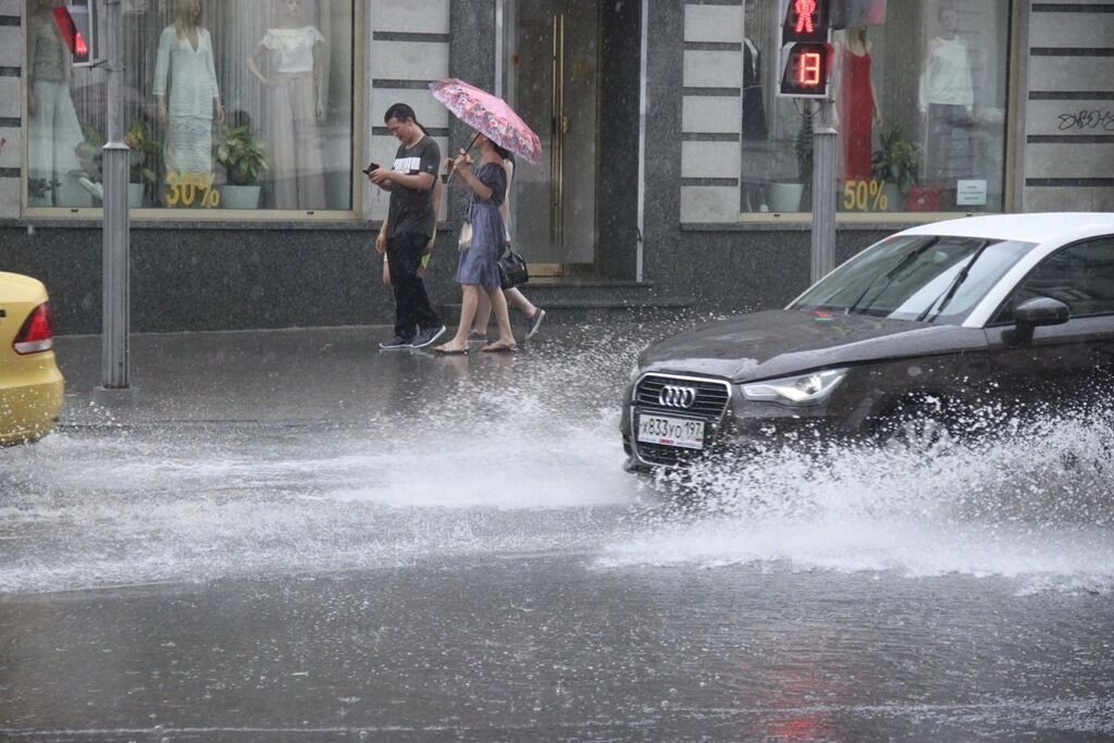 Машина в сильный дождь едет по улице Москвы