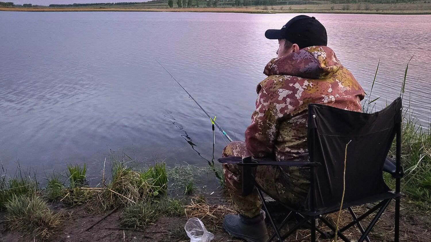 На&nbsp;фото: рыбак сидит на&nbsp;берегу