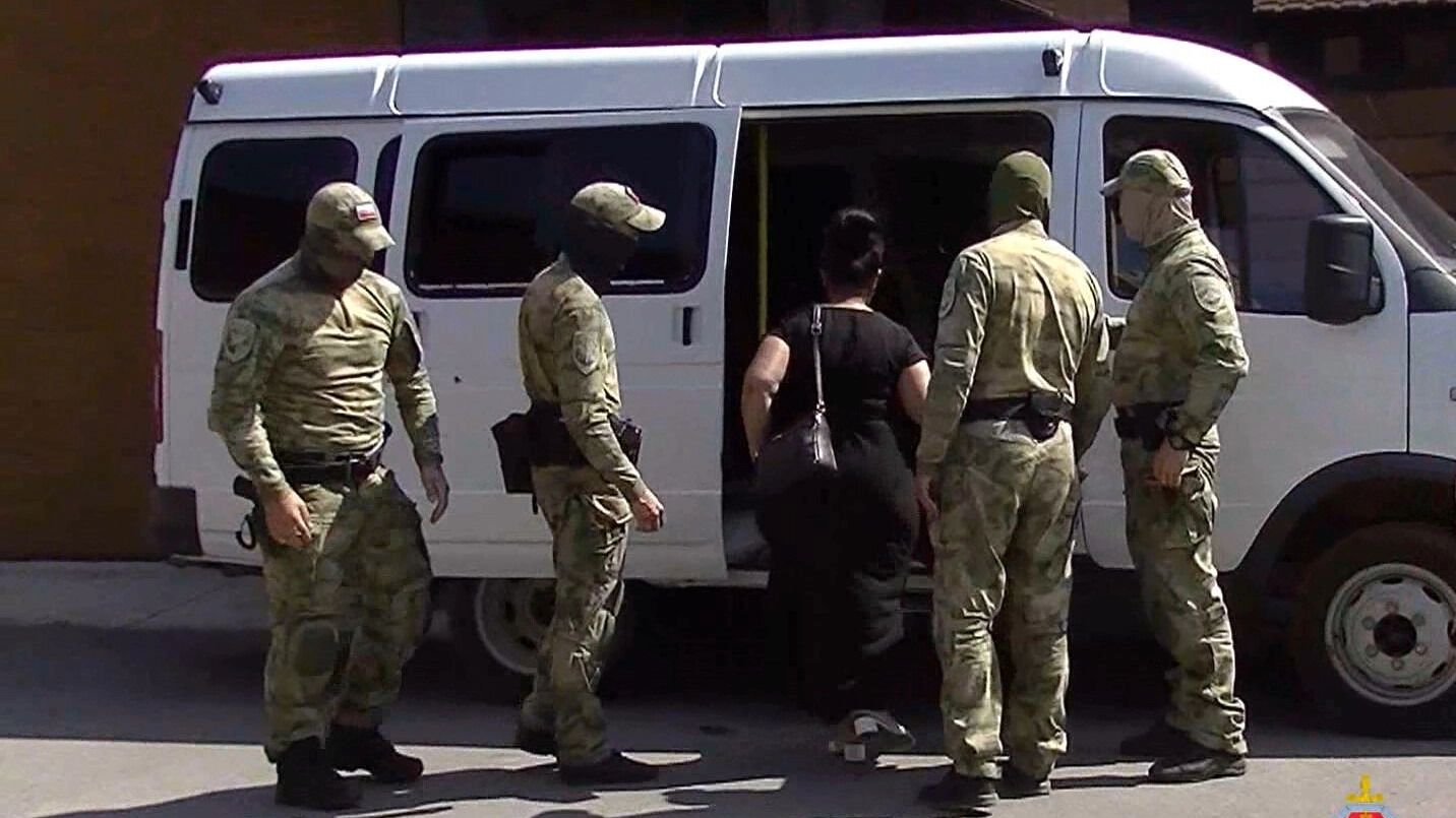 Силовики ведут задержанную женщину в машину