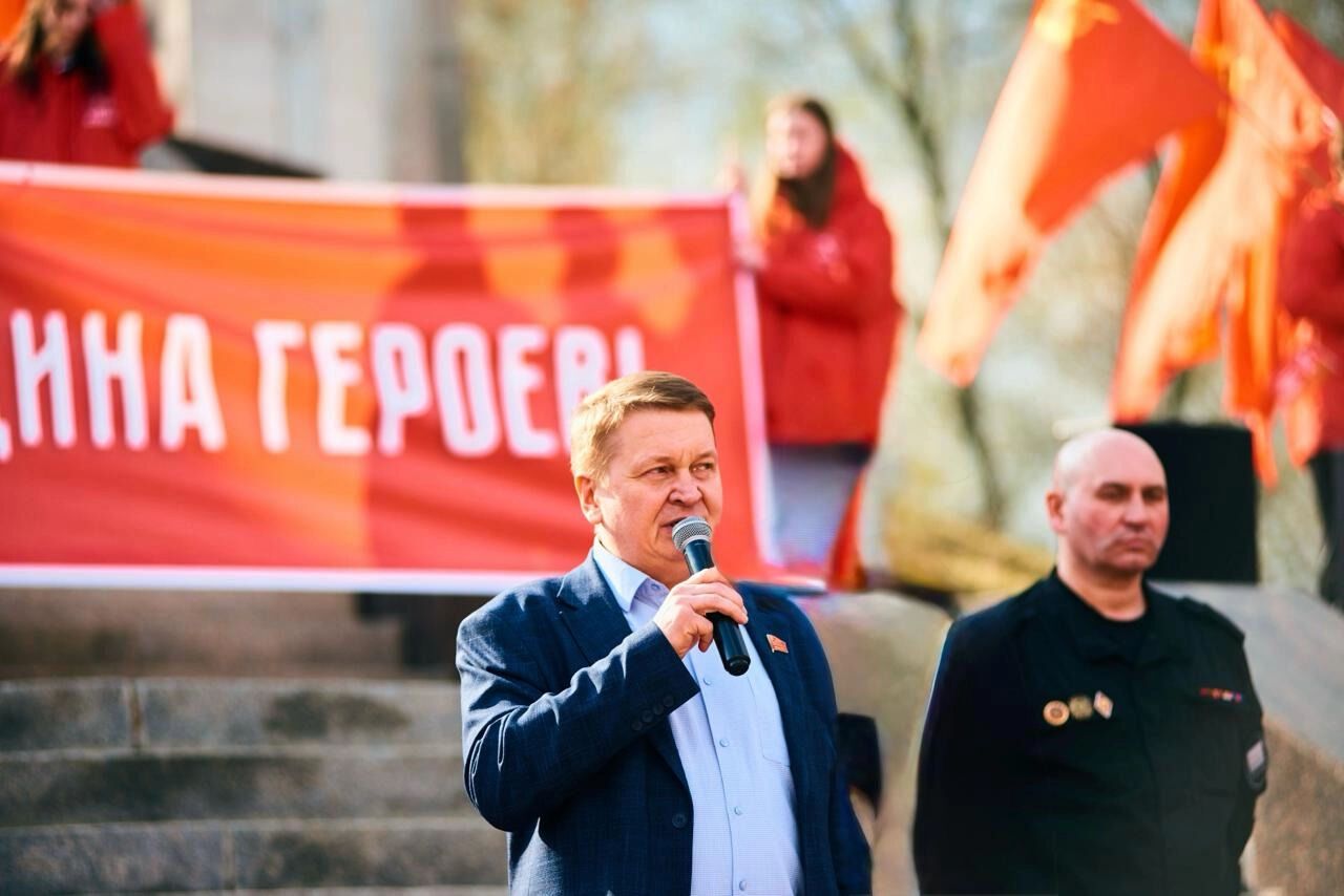 Владислав Егоров с микрофоном выступает перед публикой на фоне красного баннера