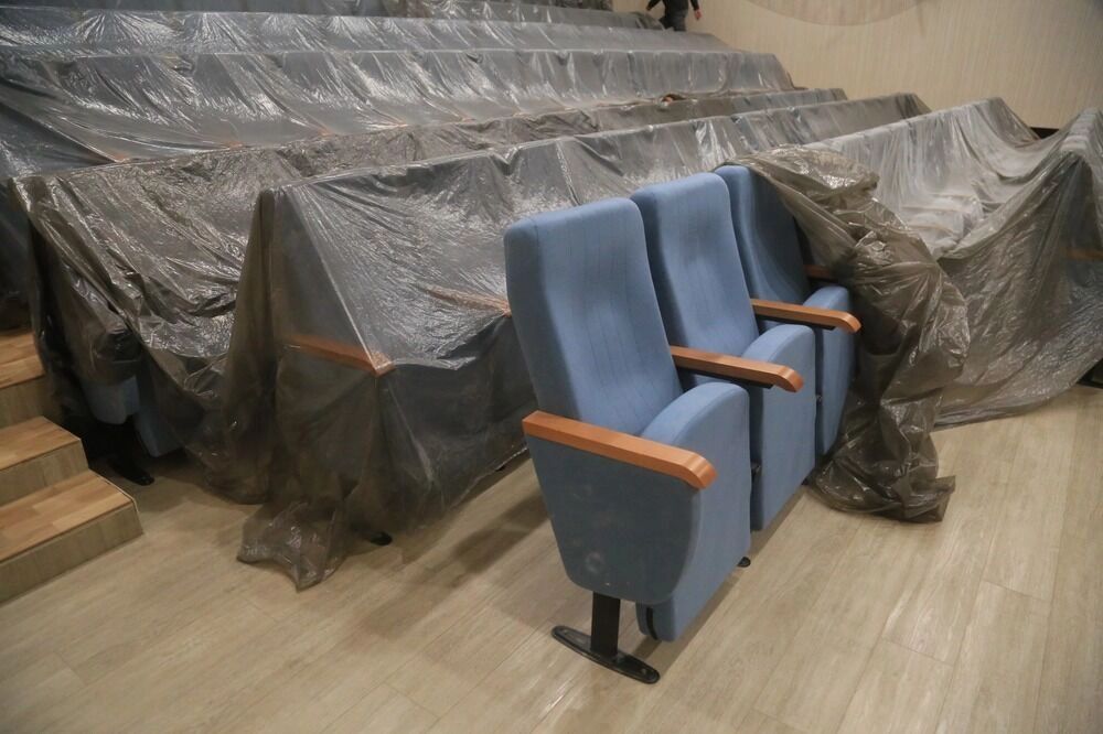 Новые кресла в зале — многие еще в чехлах